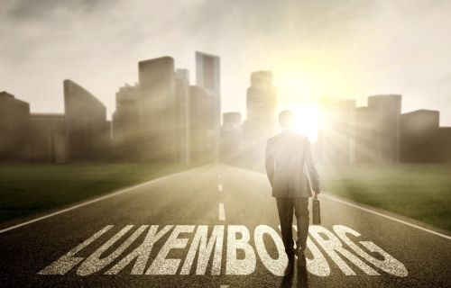 Image of male entrepreneur holding a briefcase and walking above Luxembourg word on the road